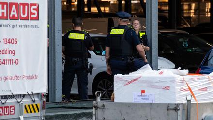 Polizisten stehen hinter Absperrbändern auf dem Gelände eines Baumarktes in Berlin-Wedding.