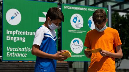 Die Geschwister-Impflinge Hugo (12 Jahre) und Urs (13 Jahre) blättern vor ihrer Impfung am Impfzentrum auf dem Messegelände in ihren Impfbüchern.