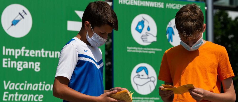 Die Geschwister-Impflinge Hugo (12 Jahre) und Urs (13 Jahre) blättern vor ihrer Impfung am Impfzentrum auf dem Messegelände in ihren Impfbüchern.