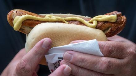 Ein Mann hält nach seiner Impfung gegen das Coronavirus eine Bratwurst in der Hand.