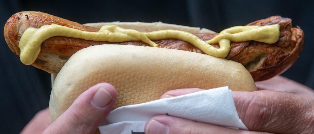 Ein Mann hält nach seiner Impfung gegen das Coronavirus eine Bratwurst in der Hand.