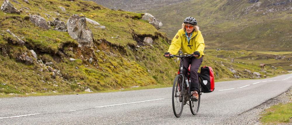 Unterwegs zu schöneren Ufern. Eine Frau mit zwei Fahrradtaschen.