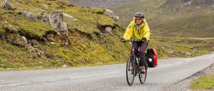 Unterwegs zu schöneren Ufern. Eine Frau mit zwei Fahrradtaschen.