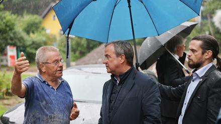 Nordrhein-Westfalens Ministerpräsident Armin Laschet unterhält sich Flutgebiet mit einem Anwohner.