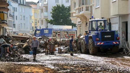 Mitarbeiter des Technischen Hilfswerks (THW) helfen bei Aufräumarbeiten nach der Unwetterkatastrophe in einer verschlammten Straße.