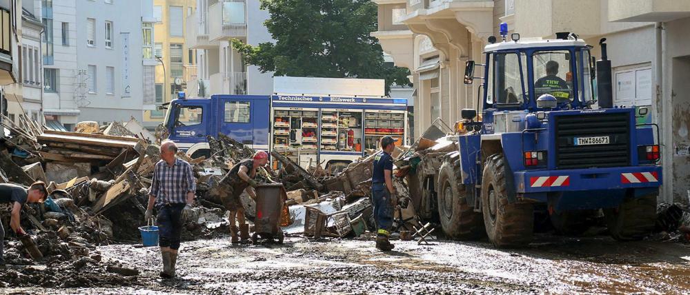 Mitarbeiter des Technischen Hilfswerks (THW) helfen bei Aufräumarbeiten nach der Unwetterkatastrophe in einer verschlammten Straße.