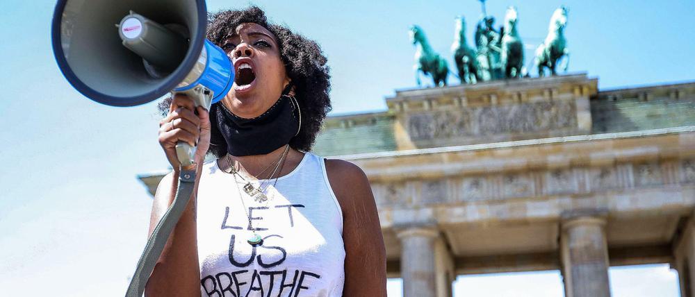 Eine Schwarze Frau demonstriert im Frühjahr 2020 vor dem Brandenburger Tor anlässlich der Tötung von George Floyd.