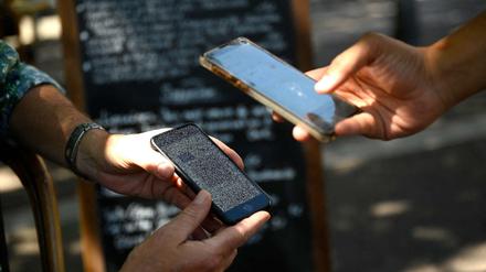 Auf der Terrasse eines Cafés in Marseille überprüft ein Kellner einen Gesundheitspass.