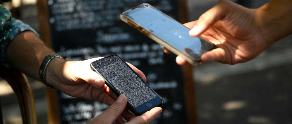 Auf der Terrasse eines Cafés in Marseille überprüft ein Kellner einen Gesundheitspass.