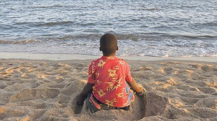 Mit den Füßen Furchen ziehen. Ein Junge am Strand von Maputo.