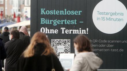 Menschen warten in Düsseldorf vor einem Testzentrum.