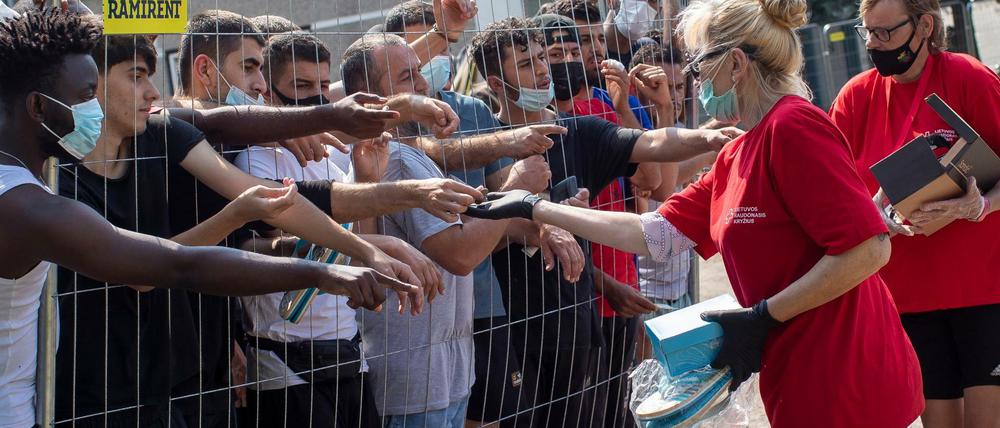 Litauer versorgen Migranten, die hinter dem Zaun eines Flüchtlingslagers stehen. 