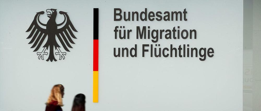 Menschen gehen an einem Bürogebäude des Bundesamtes für Migration und Flüchtlinge (BAMF) in Berlin vorbei.