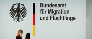 Menschen gehen an einem Bürogebäude des Bundesamtes für Migration und Flüchtlinge (BAMF) in Berlin vorbei.