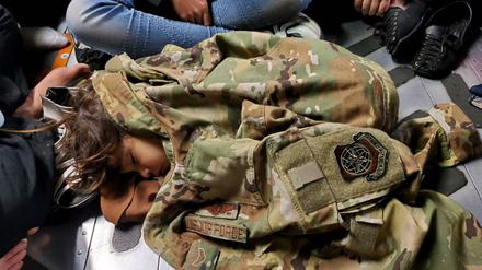 Ein Kind schläft am Flughafen Kabul unter einer US-Militärjacke.