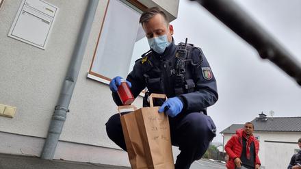 Polizisten sichern Beweismittel, nachdem Unbekannte Grabkerzen mit der Aufschrift „Impfopfer“ vor Praxen, einem Wohnhaus und dem Siegener Rathaus platziert hatten. 
