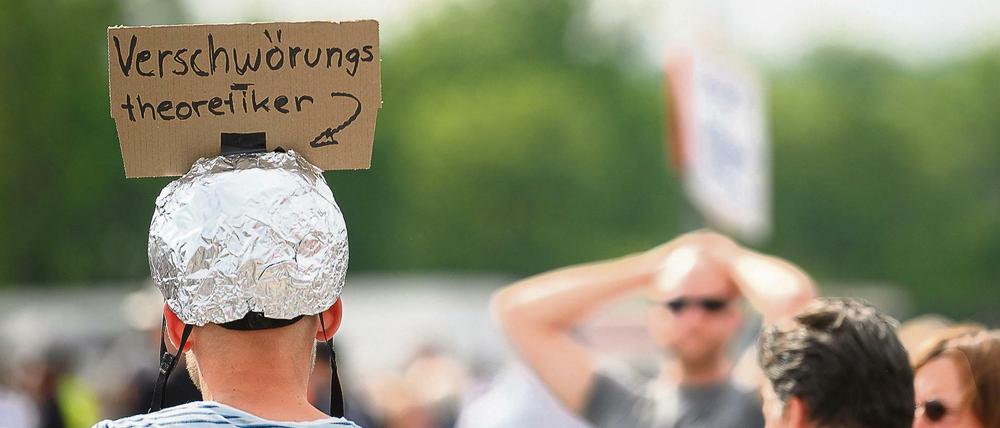 Mann mit Aluhut und Pappschild "Verschwörungstheoretiker".