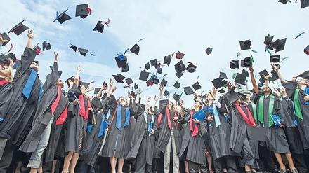 Bei einer Absolventenfeier an der Universität Bonn werfen junge Frauen und Männer ihre "Doktorhüte" in die Luft.