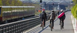  Radfahrende fahren auf einer Fahrradstrasse entlang einer S-Bahnstrecke.