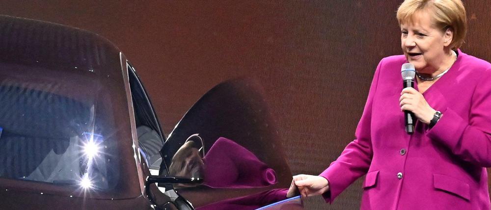 Angela Merkel steht mit einem Mikrofon in der Hand an einer geöffneten Autotür. Das Bild entstand auf der Internationalen Automobil-Ausstellung 2019.