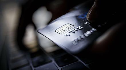 Eine Kreditkarte vom Typ VISA Card wird neben einer Computertatstatur gehalten. Oft kennen Bankkunden den Unterschied zu einer Debitkarte nicht. (Symbolbild)