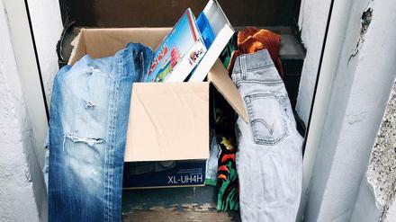 Kleidung und Bücher in einer "Verschenkbox" auf einer Eingangsstufe in Berlin.