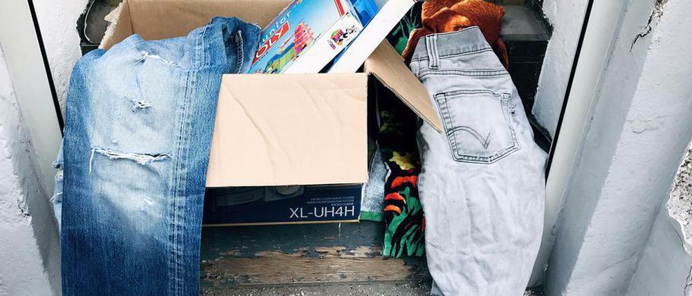 Kleidung und Bücher in einer "Verschenkbox" auf einer Eingangsstufe in Berlin.