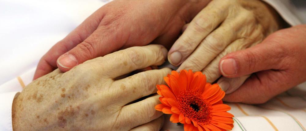In einem stationären Hospiz in Dessau-Roßlau hält eine Angehörige die Hände ihrer verstorbenen Mutter.