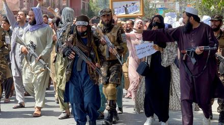 Demonstranten laufen hinter den Taliban-Kämpfern.
