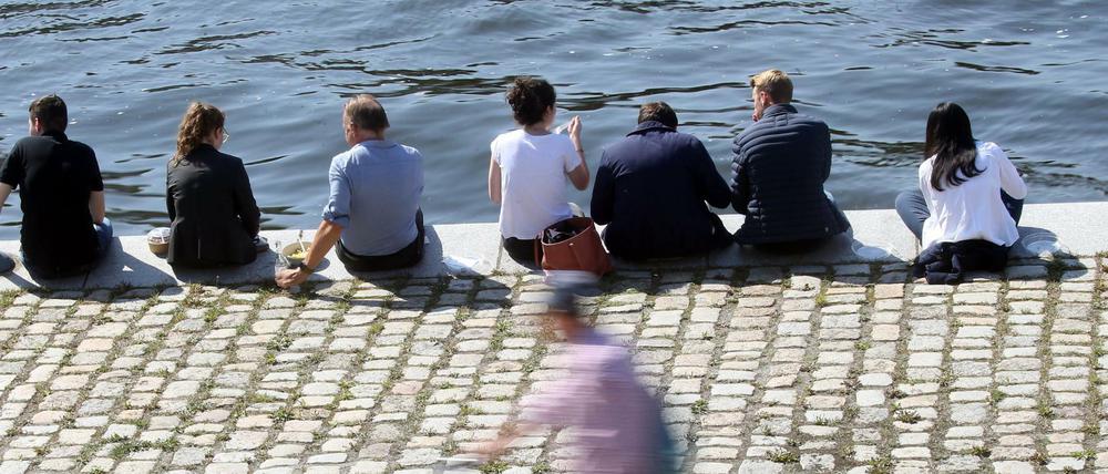 Menschen sitzen bei Temperaturen um 25 Grad Celsius am Ufer der Spree im Regierungsviertel und genießen die warme Herbstsonne, während ein Fahrradfahrer an ihnen vorbeifährt. Nach Angaben der Meteorologen wird auch in den kommenden Tage mildes Herbstwetter den Vorrang haben.