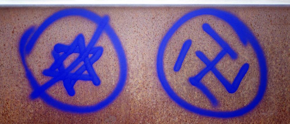 Ein Hakenkreuz und ein durchgestrichener Davidstern an einer Gedenkstätte.