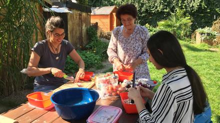 Die Freiwilligen vom Nachbarschaftsgarten Kreuzberg backen Pizza im selbstgebauten Steinofen und schneiden dafür Gemüse.