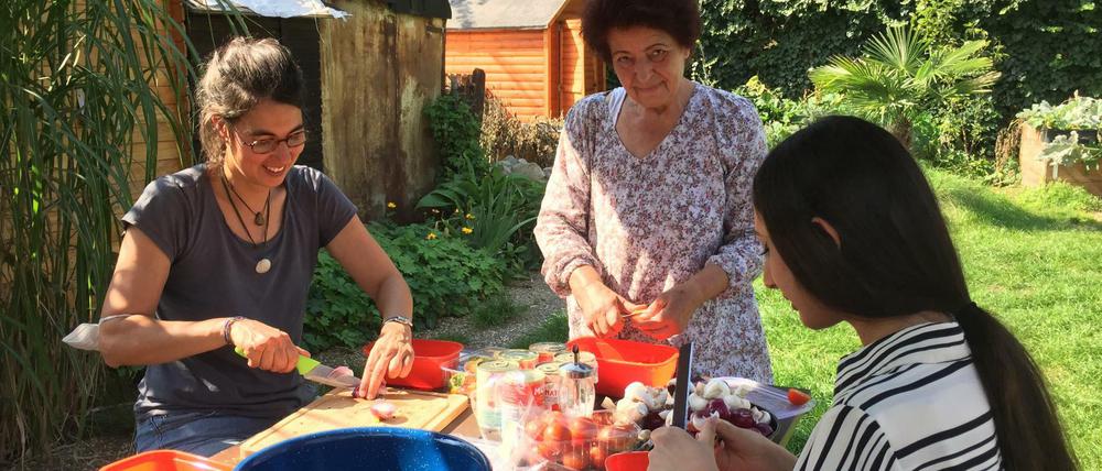 Die Freiwilligen vom Nachbarschaftsgarten Kreuzberg backen Pizza im selbstgebauten Steinofen und schneiden dafür Gemüse.