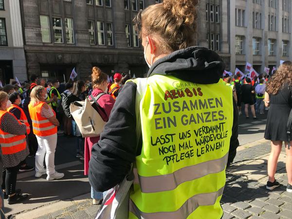 "Lasst uns verdammt noch mal würdevolle Pflege lernen!" Eine Forderung auf der Weste einer Auszubildenden der Charité vor der Finanzverwaltung.