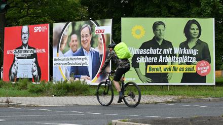 Ein Radfahrer fährt in Frankfurt am Main an Wahlplakaten mit den Spitzenkandidaten Olaf Scholz (SPD), Armin Laschet (CDU), Robert Habeck und Annalena Baerbock (Bündnis 90/Die Grünen) vorbei.