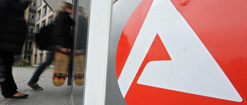 Personen gehen vor dem Schild der Arbeitsagentur in Freiburg (Baden-Württemberg) zum Eingang. 