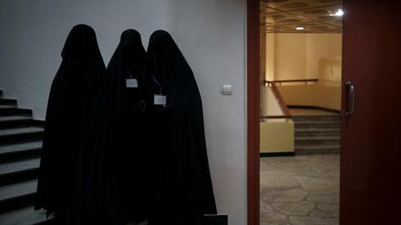 Drei in schwarze Burkas gehüllte Frauen vor einem Hörsaal der Universität in Kabul