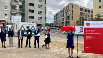 Hochschulleitung und Politiker haben sich auf einer Baustelle zum Gruppenfoto aufgestellt.