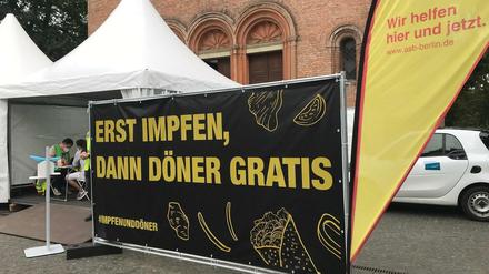 Berlin trägt dick auf: Ein Werbeschild für die Impfaktion auf dem Leopoldplatz, dahinter das Impfzelt.