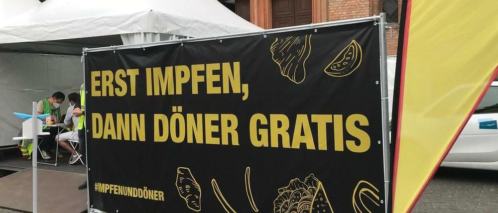 Berlin trägt dick auf: Ein Werbeschild für die Impfaktion auf dem Leopoldplatz, dahinter das Impfzelt.