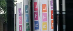 Fahnen des Fernsehsenders RTL stehen auf dem Platz vor dem Firmengebäude.