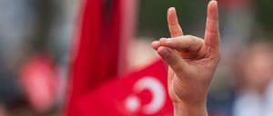 Eine Hand zeigt den "Wolfsgruß" vor türkischen Flagge in München 2016.