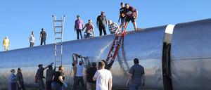 Menschen bohren den umgestürzten Waggon auf.