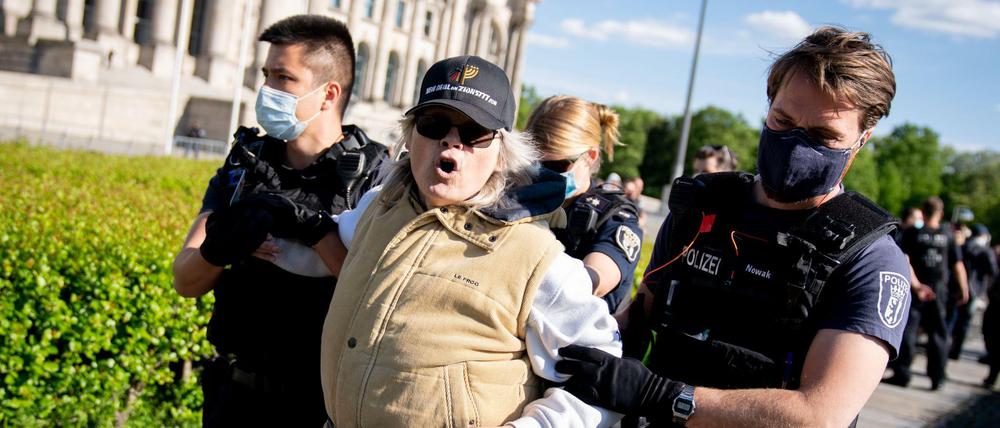 Eine Teilnehmerin wird von Polizeibeamten mit Mund-Nasen-Schutz vor dem Reichstagsgebäude am Rande einer Demonstration gegen eine Impfpflicht und gegen die freiheitseinschränkenden Maßnahmen der Bundesregierung im Rahmen der Ausbreitung des Coronavirus abgeführt.