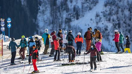 Skifahrer stehen an einer Piste.