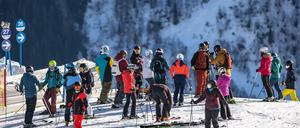 Skifahrer stehen an einer Piste.