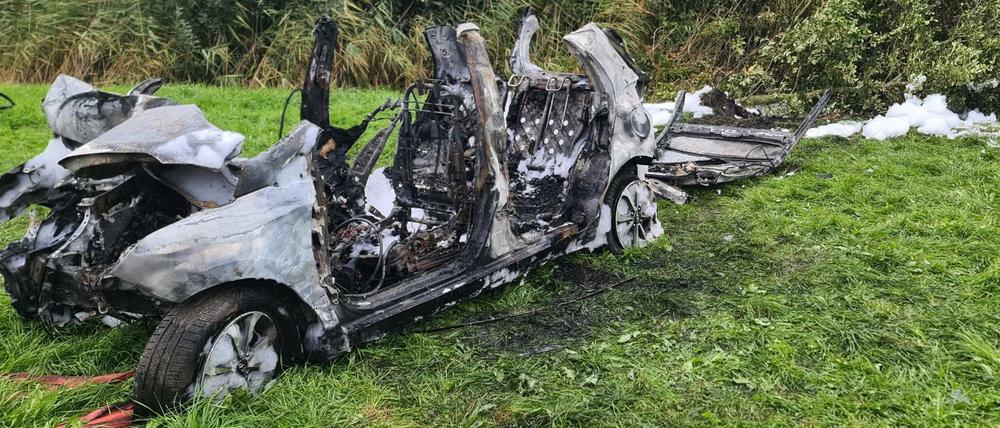 Das ausgebrannte Wrack des Autos steht bei Brunsbüttel am Fahrbahnrand.