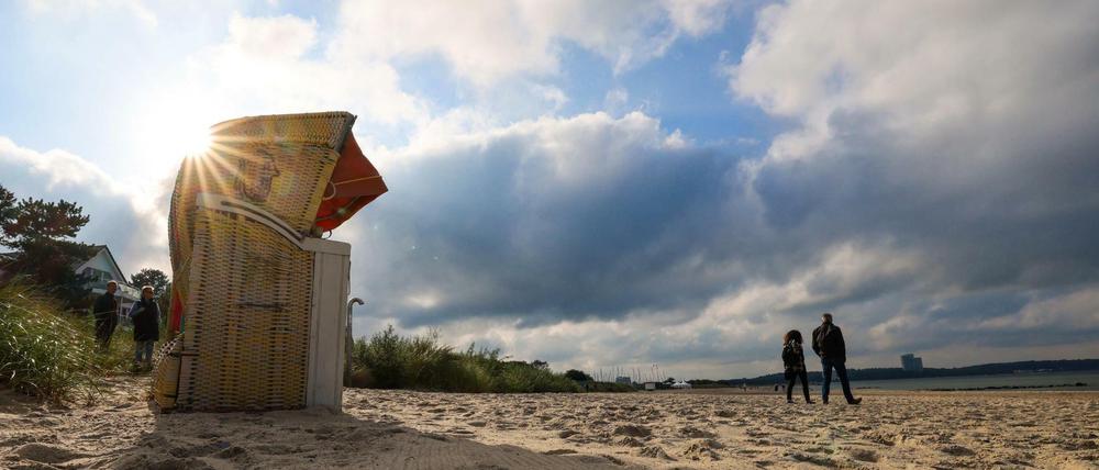 Menschen spazieren am Ostseestrand von Niendorf.