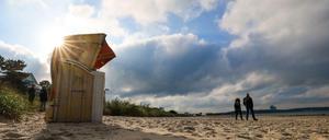 Menschen spazieren am Ostseestrand von Niendorf.