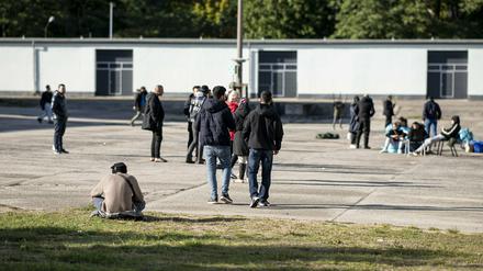 Asylsuchende laufen in der Erstaufnahmeeinrichtung Eisenhüttenstadt über einen Platz. 